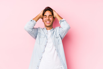 Young caucasian man posing in a pink background isolated laughs joyfully keeping hands on head. Happiness concept.