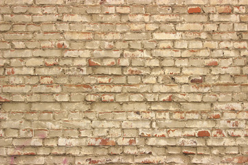 Old ragged, weathered brick wall painted with white lime