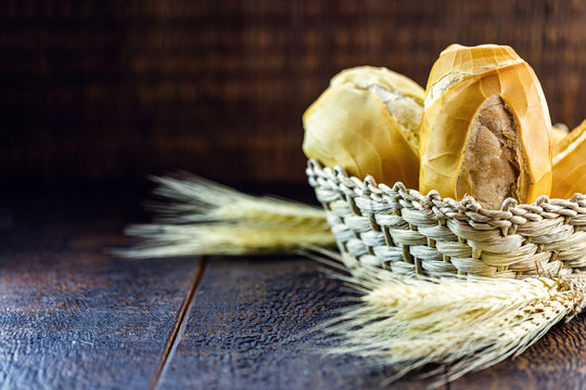 typical Brazilian bakery bread, in straw basket on wooden background. Known as French bread.