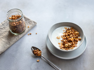 natural yogurt with granola, nuts in a bowl. healthy breakfast, snack. gray concrete background. horizontal image. copy space