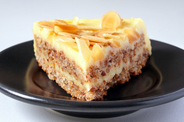 A piece of cake on a plate. Walnut chips on the surface of the cake.