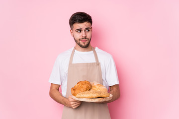 Young caucasian baker man isolated confused, feels doubtful and unsure.