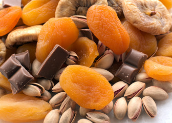Dried figs  chocolates, peanuts  and apricots on white background