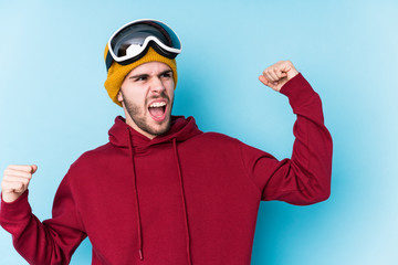 Young caucasian man wearing a ski clothes isolated raising fist after a victory, winner concept.