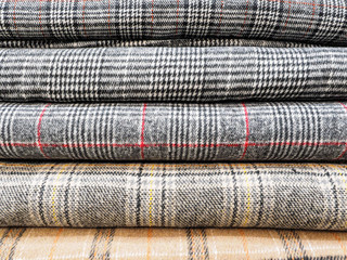 Original and fashionable plaid fabrics close-up. Large assortment of fabrics in the store. A tailor...