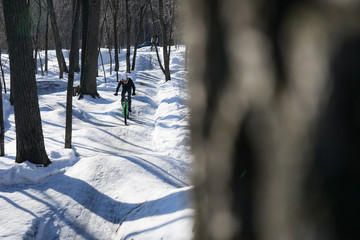 rider rides on a pump track in winter. The cyclist accelerates to jump on dirt jumping. slippery...