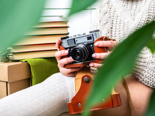 Girl sitting on the floor surrounded by books and holding a retro camera