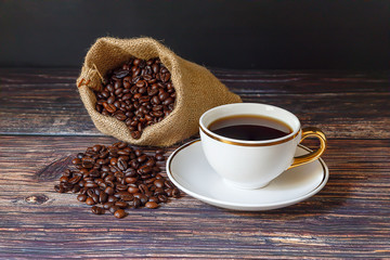  Black coffee in white cups and coffee beans on a black wooden floor.