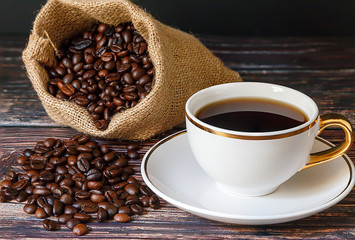  Black coffee in white cups and coffee beans on a black wooden floor.