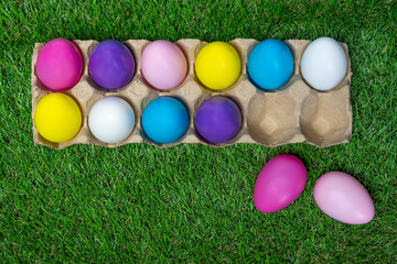 Fototapeta na wymiar Colored Easter eggs in egg carton on grass background. 