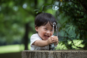 公園で水遊びをする無邪気で元気な男の子.