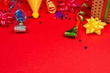 Festive golden and purple stars of confetti  and a present, birthday caps on a red background.