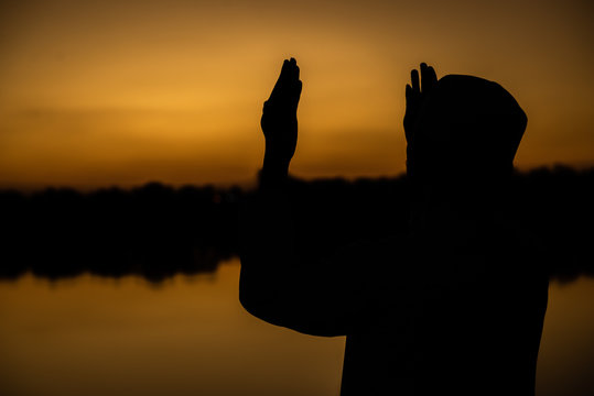 Silhouette Young asian muslim man praying on sunset,Ramadan festival concept