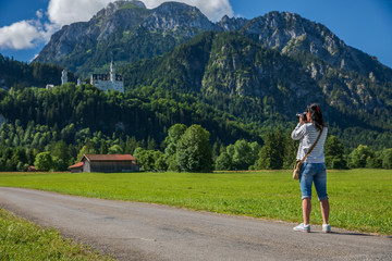 Female tourist taking photos Neuschwanstein Castle Bavarian Alps Germany