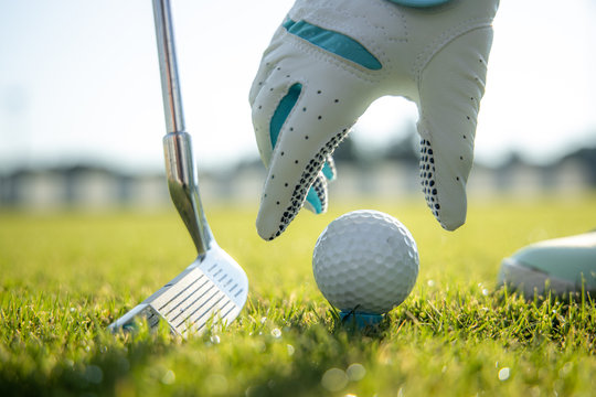 Hand In Glove Placing Golf Ball On Tee