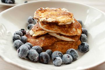 Low Carb Keto Diet Pancakes from almond coconut flour with blueberries, cream on white plate background close up view. Selective focus. Copy space. Ketogenic concept
