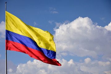 National flag and colors of Colombia against sky and clouds in South America