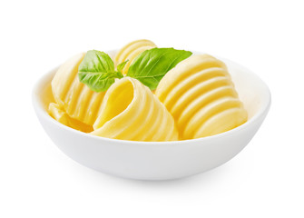 Butter curls or butter rolls in white bowl with fresh basil leaves isolated on white background.