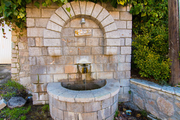 An old stone public faucet with fresh water in the countryside in Greece