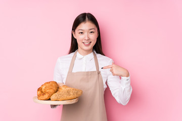 Young chinese baker woman isolated person pointing by hand to a shirt copy space, proud and confident