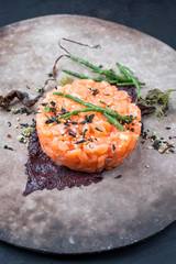 Gourmet Lachs Fisch Tartar roh mit Meeresalgen, Nori und japanische Gewürze als closeup auf einem Modern Design Teller