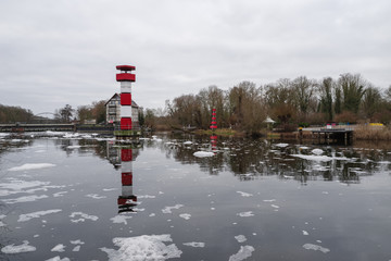 Lighthouse in river against cloudy sky