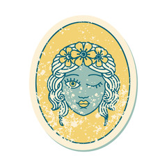 distressed sticker tattoo style icon of a maiden with crown of flowers winking