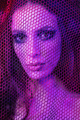 Colorful portrait of a sensual young woman behind a red fence