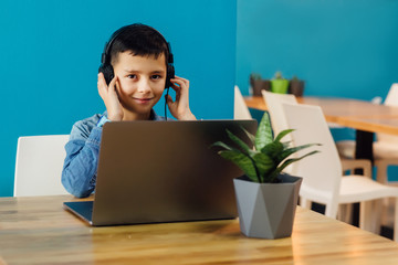 Gaming video games, small boy playing game with headphones enjoying sitting at modern room.