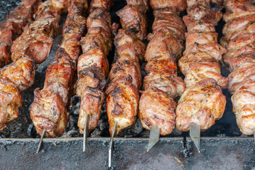 Cooking barbecue on coals. Pieces of rosy meat strung on metal skewers. Harmful and hazardous food...