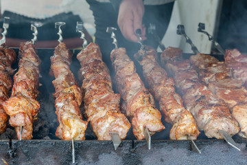 Cooking barbecue on coals. Pieces of rosy meat strung on metal skewers. Harmful and hazardous food...