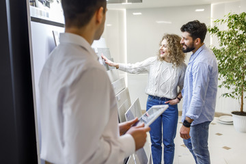 Successful and happy caucasian couple choosing ceramic tiles for their new house repairment in the building shop