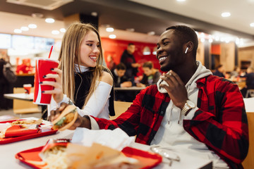 Happy loving couple enjoying breakfast in burger bar. Love, dating, food, lifestyle concept.