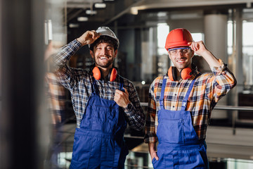Two young builders in working uniform and helmets ready for a work.