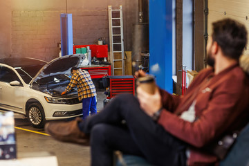 repairman working with the car in the modern service center while customer waiting