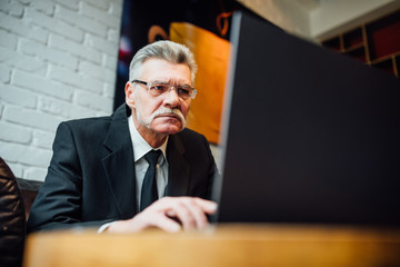 Senior mature or  business man having a lunch break in a coffee shop and working on his laptop