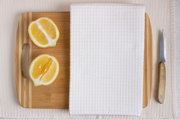 White kitchen waffle towel on wooden cutting board with fresh lemons. Product design - 325404491