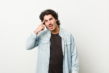 Young handsome man against a white background showing a disappointment gesture with forefinger.