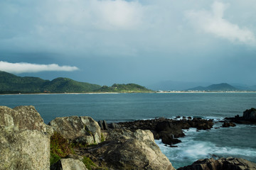 Fototapeta na wymiar View of Armação beach shore line during the day. Rain clouds and sun. Long exposure shot.