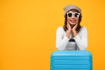 Portrait of female traveler with blue suitcase in colorful background, travel and insurance concept