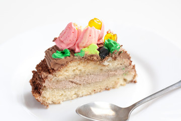 A piece of sponge cake with colored cream on a white plate