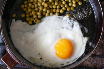 Breakfast, fried eggs and peas in a frying pan