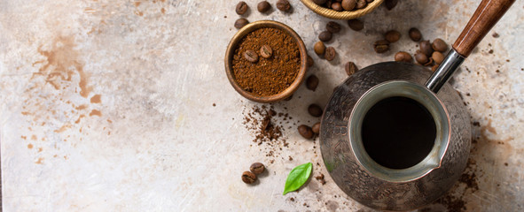 Morning coffee concept. Turkish coffee in Turk and coffee beans on a stone or slate countertop. Top view flat lay background. Copy space. Banner.