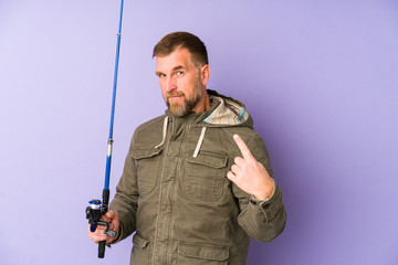 Senior fisherman isolated on purple background pointing with finger at you as if inviting come closer.
