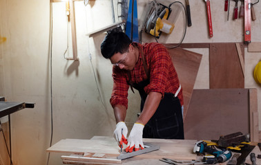 Handsome man using pencil drawing on timber board, doing wood work at factory,Handmade design,The carpenter