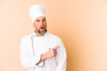 Chef man isolated on beige background pointing to the side