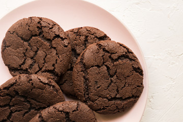 Top view of chocolate chip cookies on a pink plate on white concrete background. From above. copy space