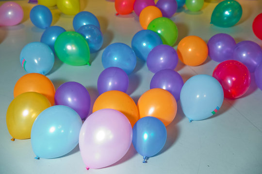 Flat lay of colorful balloons . holiday, children's party, a games room, a box filled with small colored balls . Different color balloons on the floor .