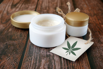 cannabis cosmetic, hemp cream in dose with cannabis leaf symbol in blank on wooden background,...