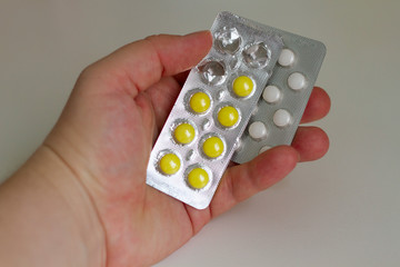 Blisters with white and yellow pills in a humans`s hand